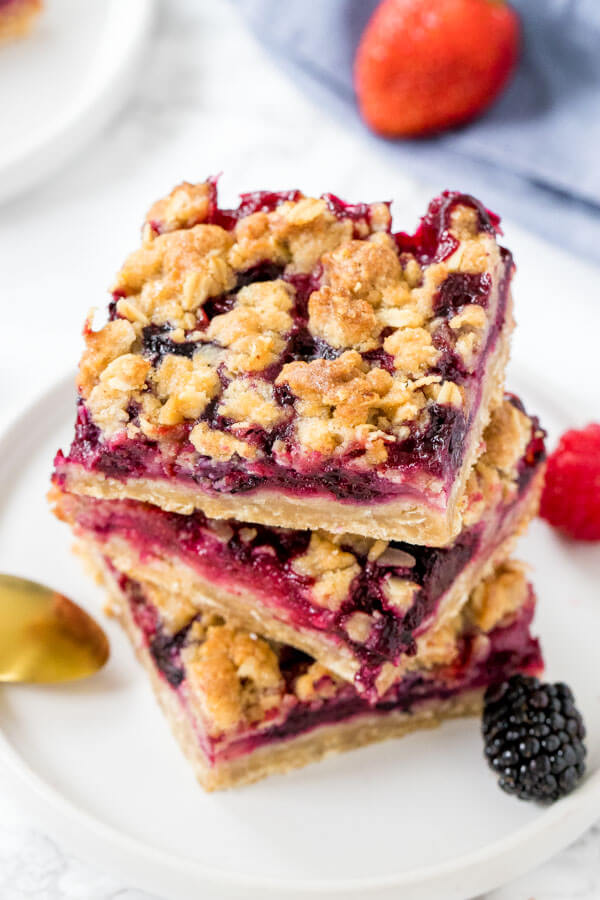 Overhead view of 3 mixed berry oatmeal crumble bars stacked on top of each other. 