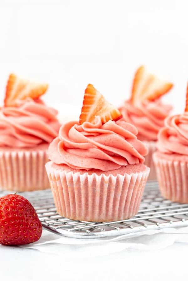 strawberry cupcakes with strawberry frosting on a wire cooling rack