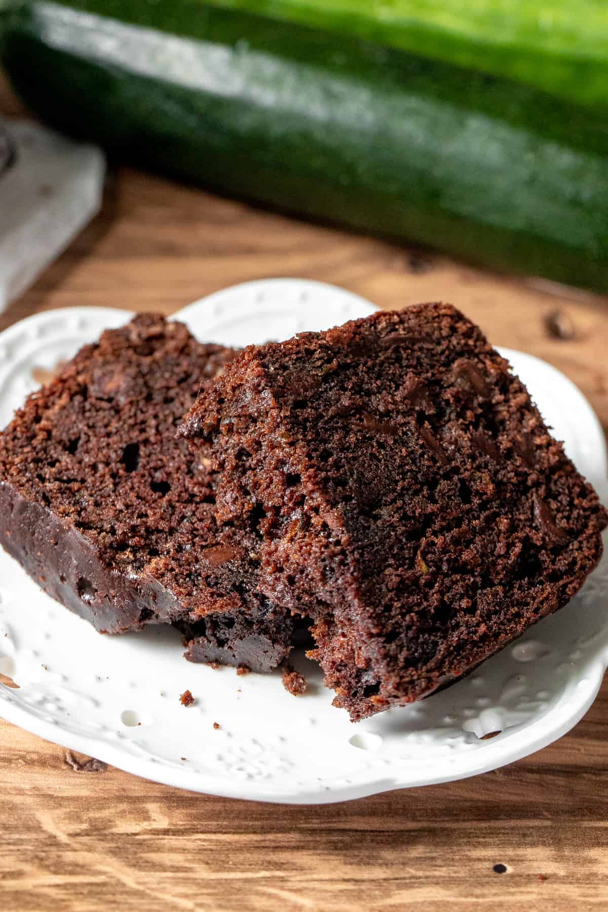 Slice of chocolate zucchini loaf broken in half on a plate.