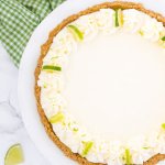 Overhead view of an entire no bake key lime pie with whipped cream and lime slices to decorate.