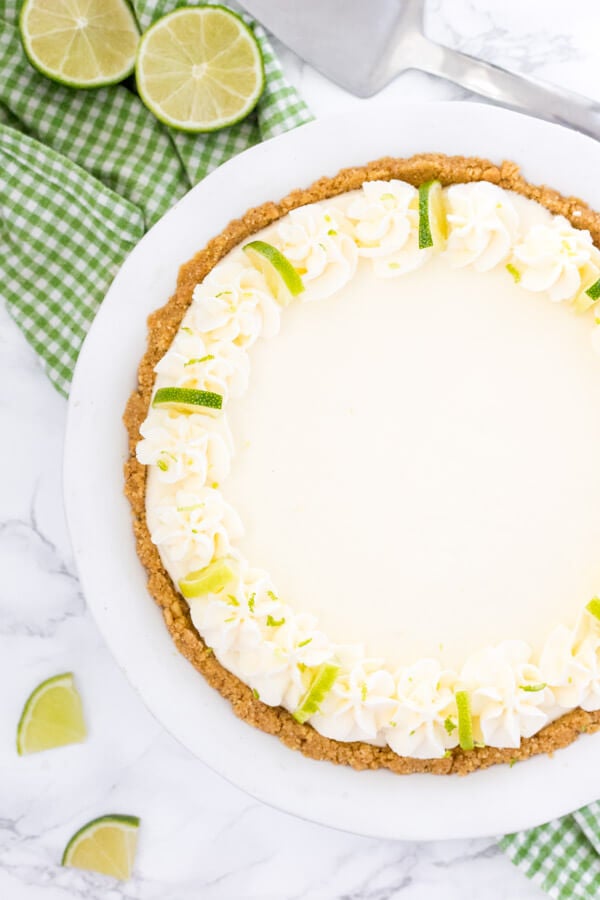 Overhead view of an entire no bake key lime pie with whipped cream and lime slices to decorate.