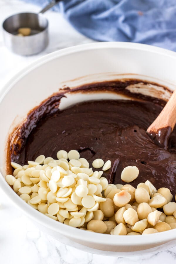 A bowl of brownie batter right before stirring in white chocolate chips and macadamia nuts. 