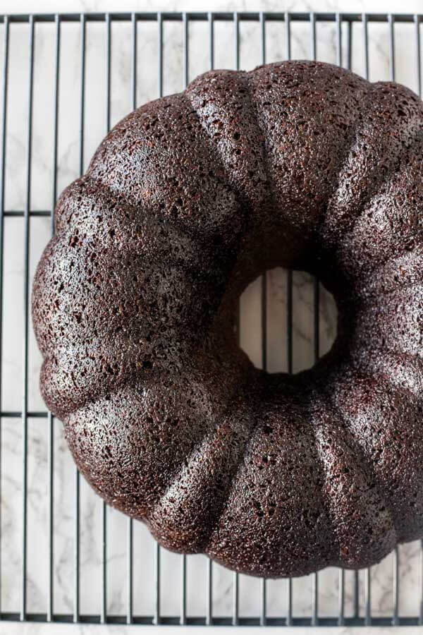 A chocolate bundt cake after being released from the pan, as it cools on a wire rack 