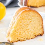 A slice of moist lemon bundt cake with a drizzle of lemon glaze on a white plate.