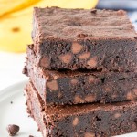 A stack of 3 fudgy banana brownies, shown from the side to highlight their moist, fudgy texture.