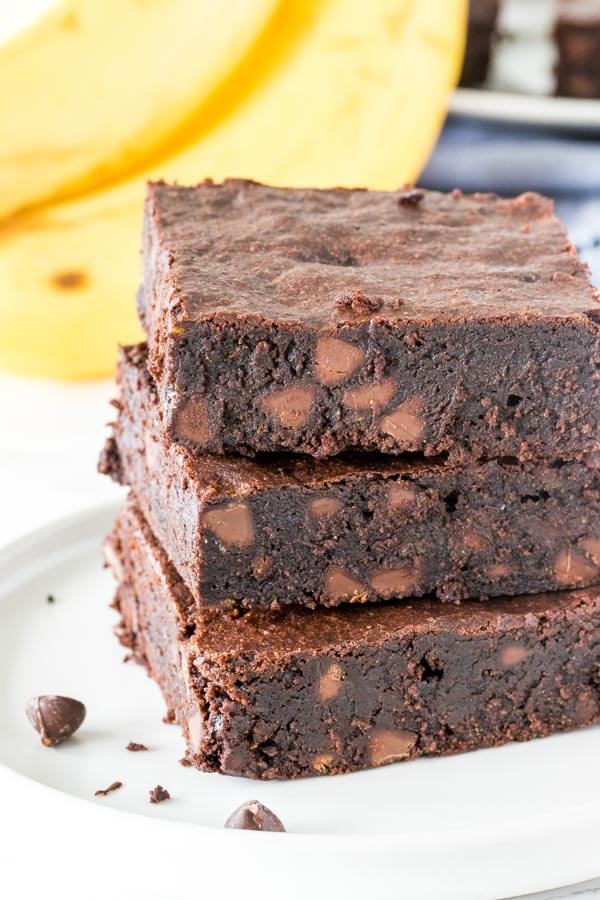 A stack of 3 fudgy banana brownies, shown from the side to highlight their moist, fudgy texture. 