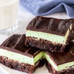 A plate of mint brownies with a fudgy brownie base, mint frosting middle, and chocolate ganache on top.