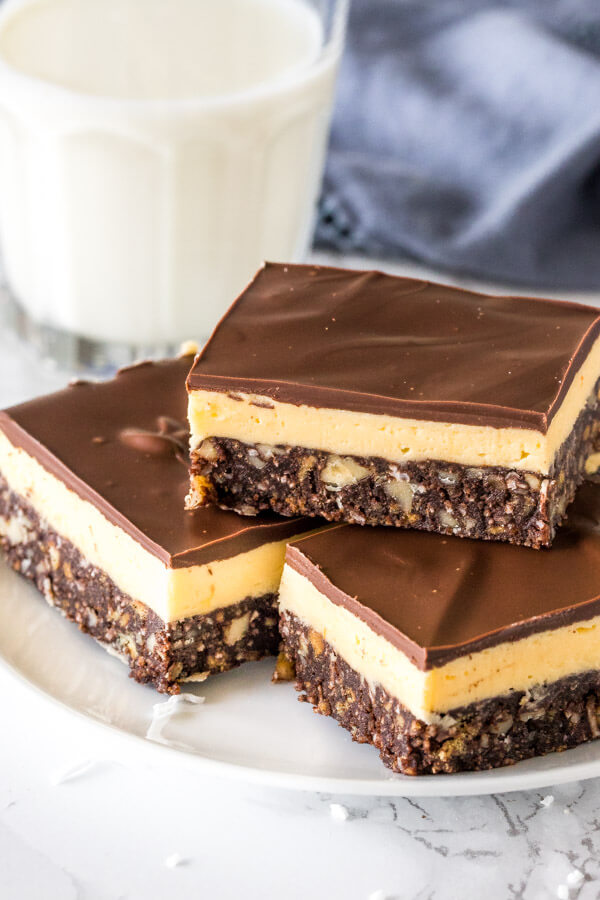 A plate of classic Nanaimo bars stacked with custard buttercream filling and chocolate on top, 