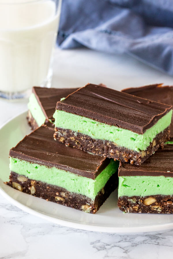 A plate of mint Nanaimo bars with a glass of milk. 