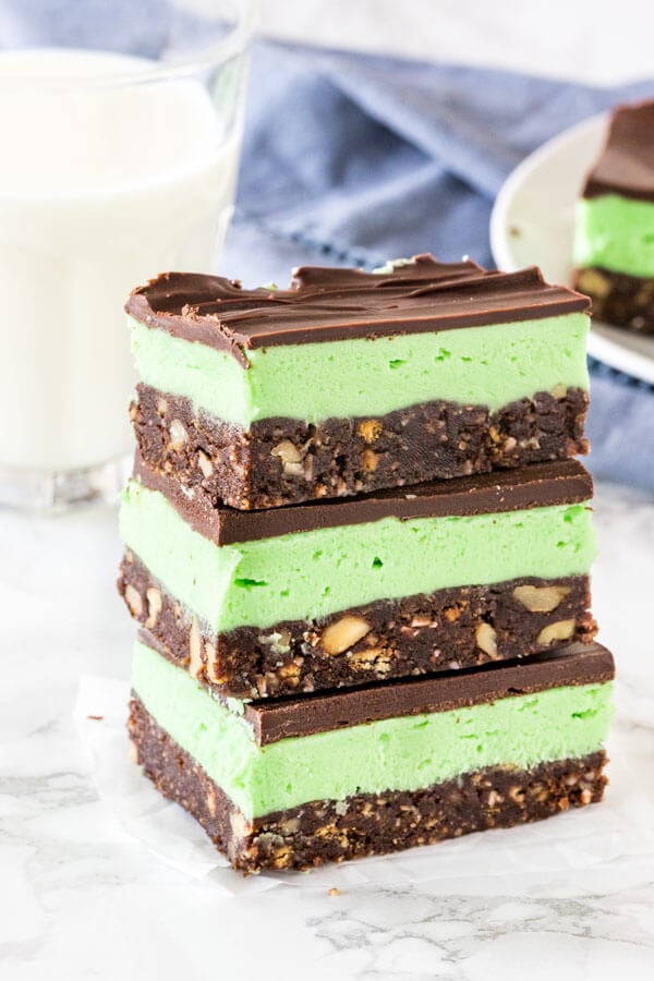 A stack of 3 mint Nanaimo bars shot from the side to see the 3 layers. 