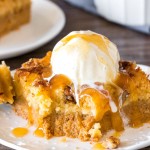 A slice of pumpkin dump cake showing the pumpkin pudding bottom and gooey butter cake topping served with ice cream.