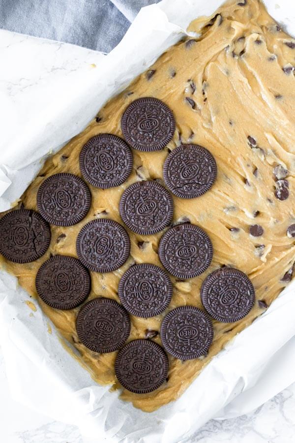 How to make slutty brownies - Spread the cookie dough onto the bottom of the pan, then place a layer of Oreo cookies over top. 