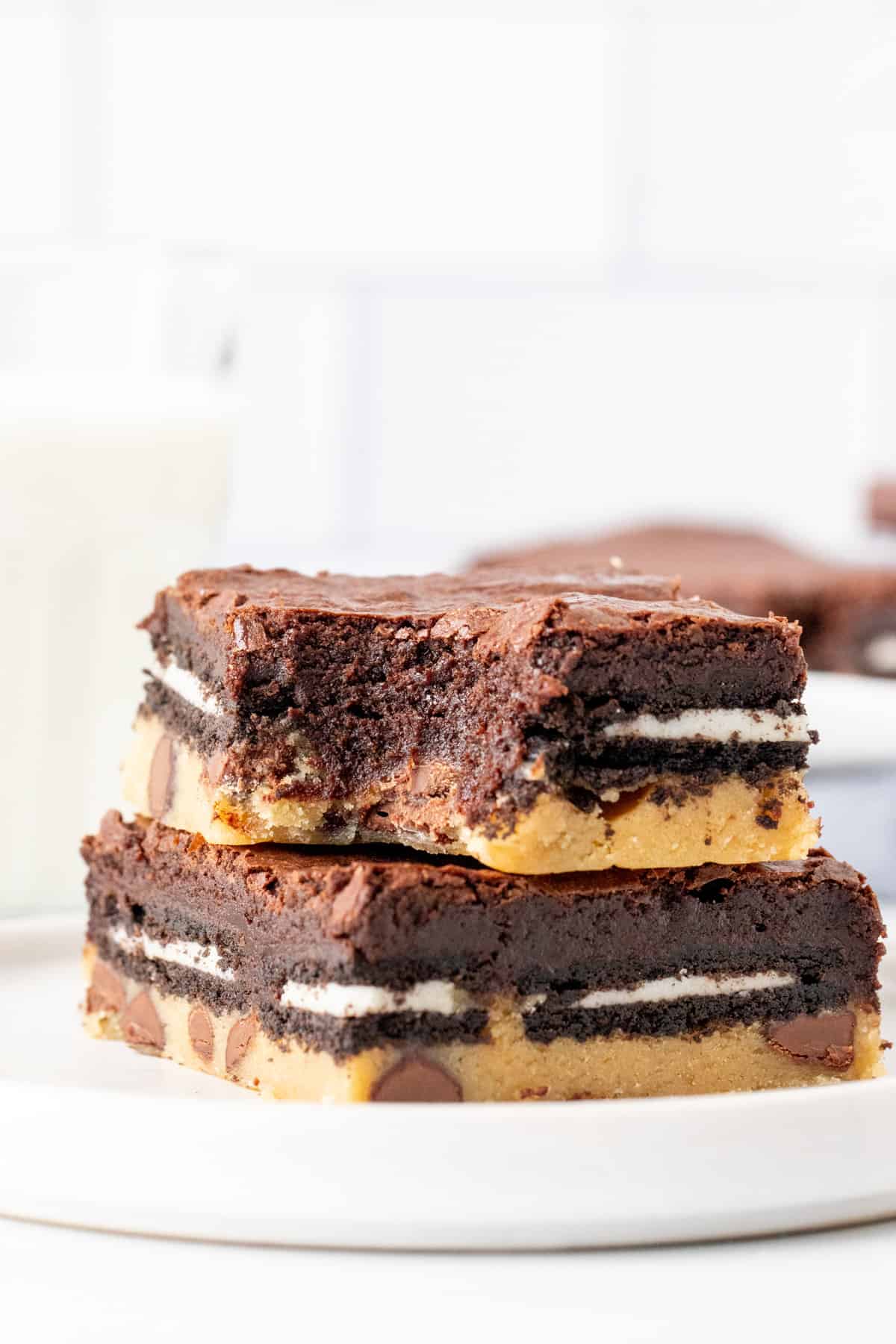 Two Oreo cookie dough brownies, one on top of each other, with a bite taken out.
