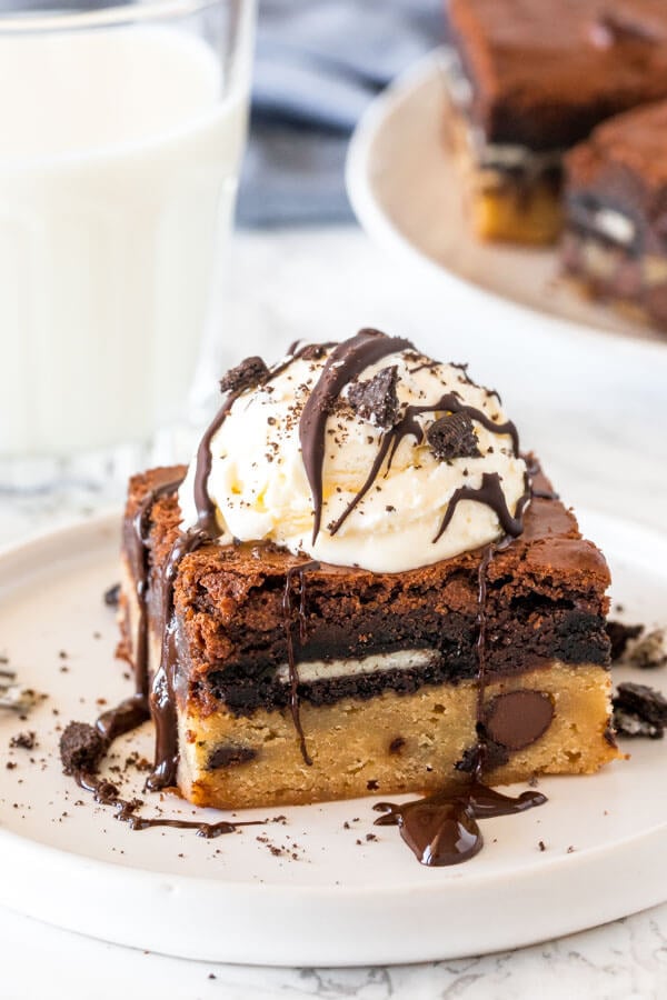 A cookie dough oreo brownie with a scoop of ice cream, chocolate sauce and oreo crumbs on top. 