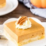 A slice of pumpkin pie bars with easy shortbread crust and whipped cream on top.