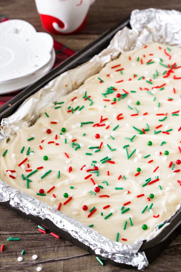 A 9x13 inch pan of frosted Christmas cookie bars with sprinkles.
