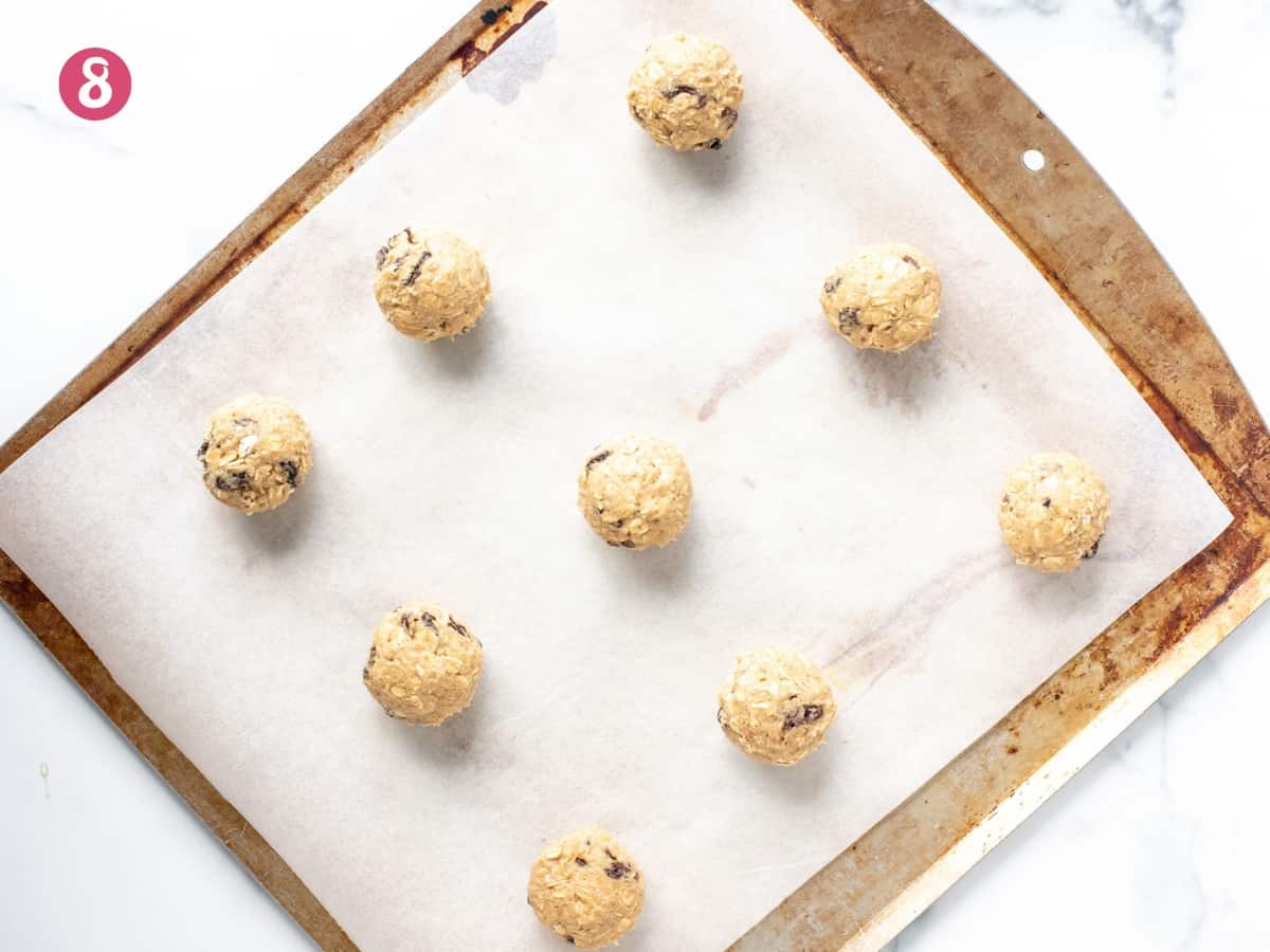 Lined cookie sheet of oatmeal raisin cookie dough balls