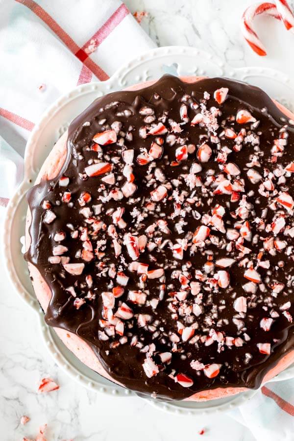 Overhead shot of an entire peppermint cheesecake with chocolate ganache and crushed candy canes on top.