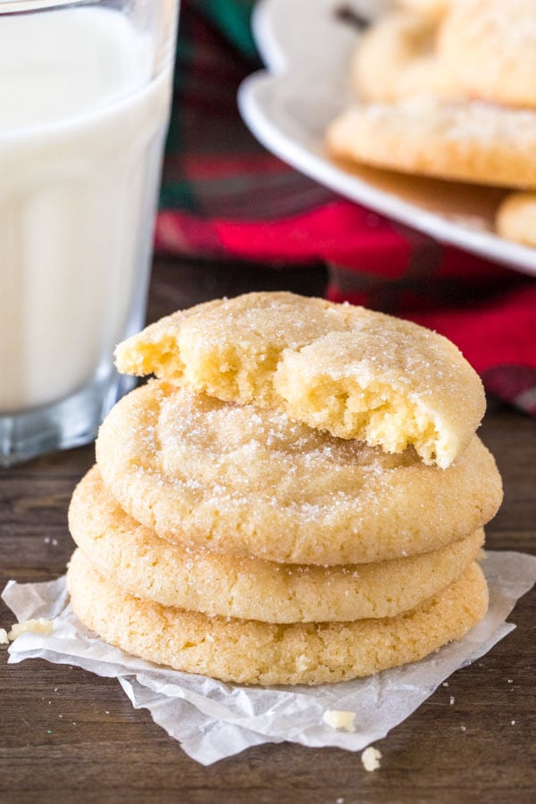 A stack of chewy sugar cookies with the top cookie broken in half. 