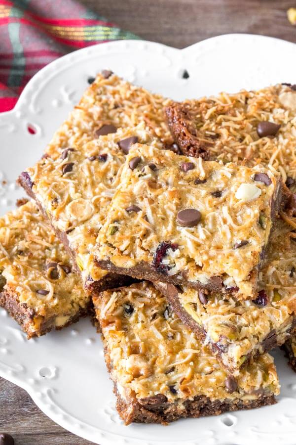 A plate of Christmas magic cookie bars cut into squares and stacked. 