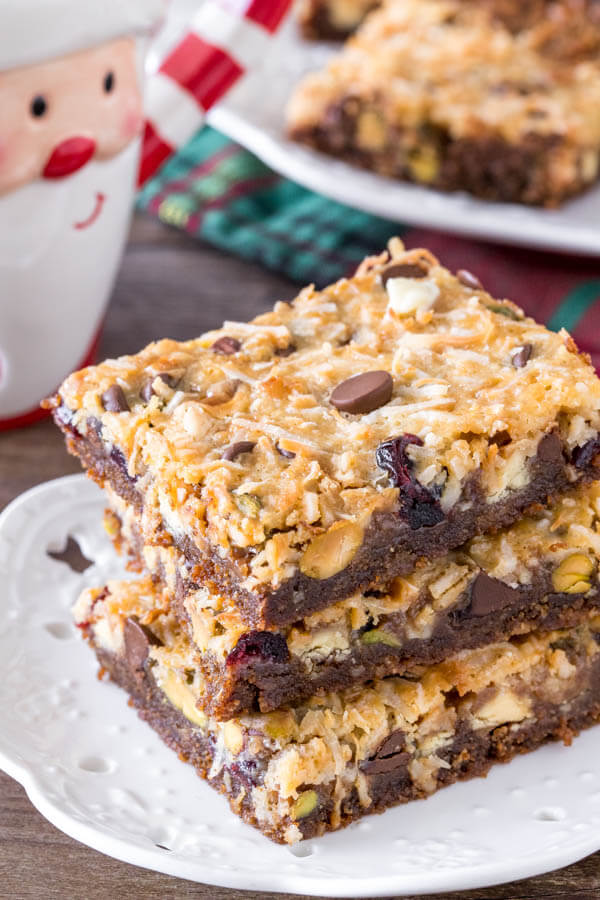 A stack of 3 christmas magic cookie bars with a gingersnap crust and coconut topping.