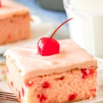 A slice of maraschino cherry cake with cherry frosting and a cherry on top