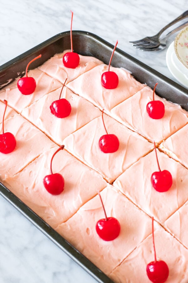 A 9x13 inch pan of maraschino cherry cake sliced into pieces. 