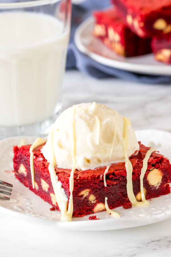 Red velvet brownie on a white plate with a scoop of vanilla ice cream on top. 