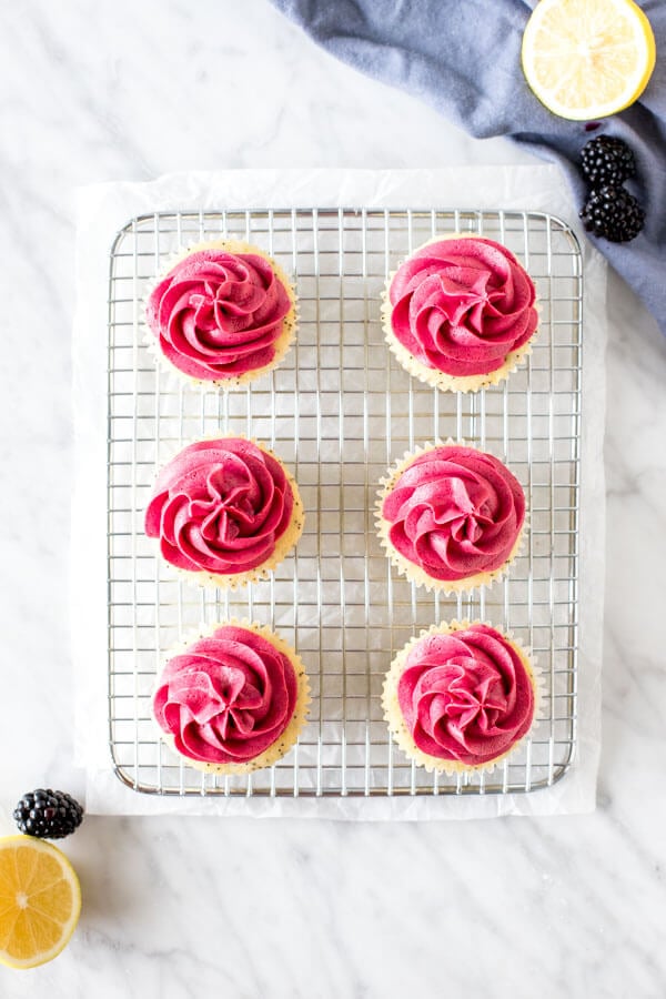 Cupcakes with blackberry frosting on a cooling rack, shot from above. 