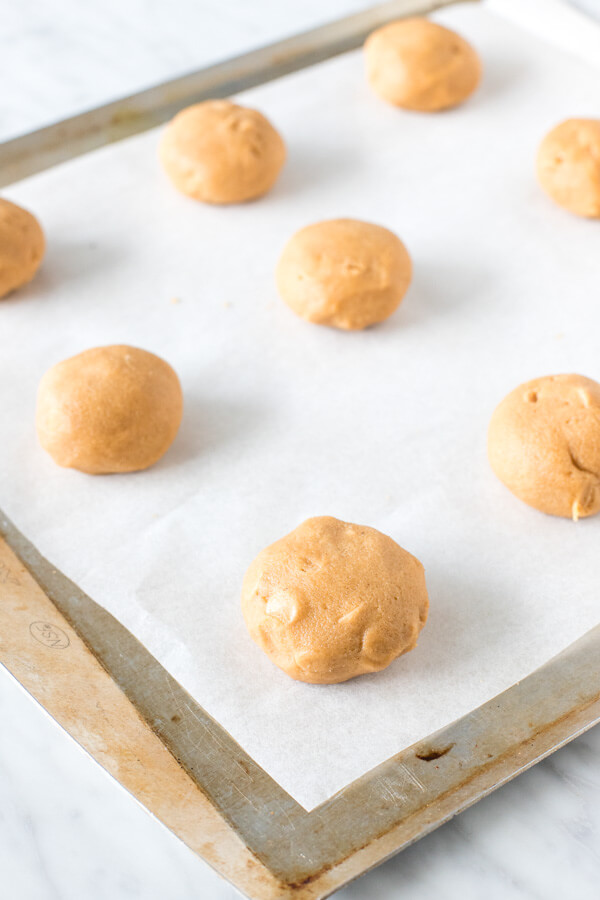 Cookie dough balls on a lined cookie sheet. 