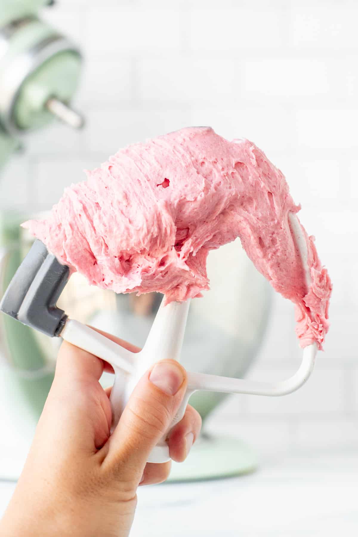 Kitchen beater with pink raspberry buttercream on it