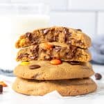 Stack of Reese's Pieces peanut butter cookies, with the top cookie broken in half.