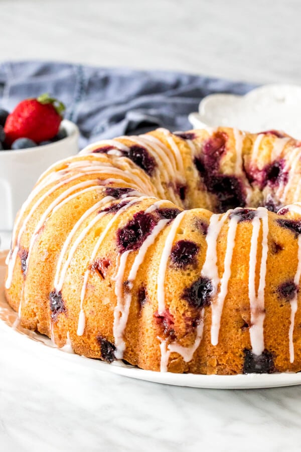A berry bundt cake on a plate with a drizzle of glaze on top