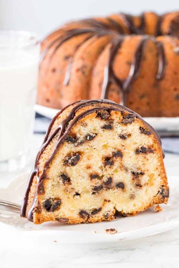 Slice of chocolate chip bundt cake on a plate with glass of milk. 