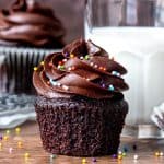 Chocolate cupcake with paper removed beside glass of milk