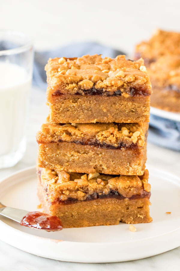 Stack of 3 peanut butter and jelly bars with a glass of milk. 