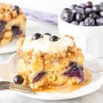 Slice of blueberry french toast casserole with whipped cream on top.