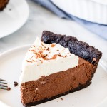 Slice of chocolate mousse pie with whipped cream on a white plate.