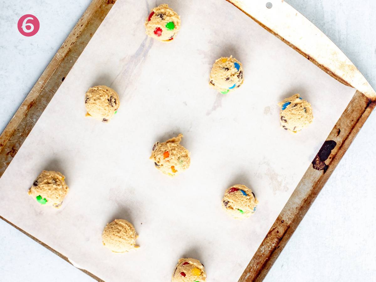 Lined cookie sheet with M&M cookie dough balls
