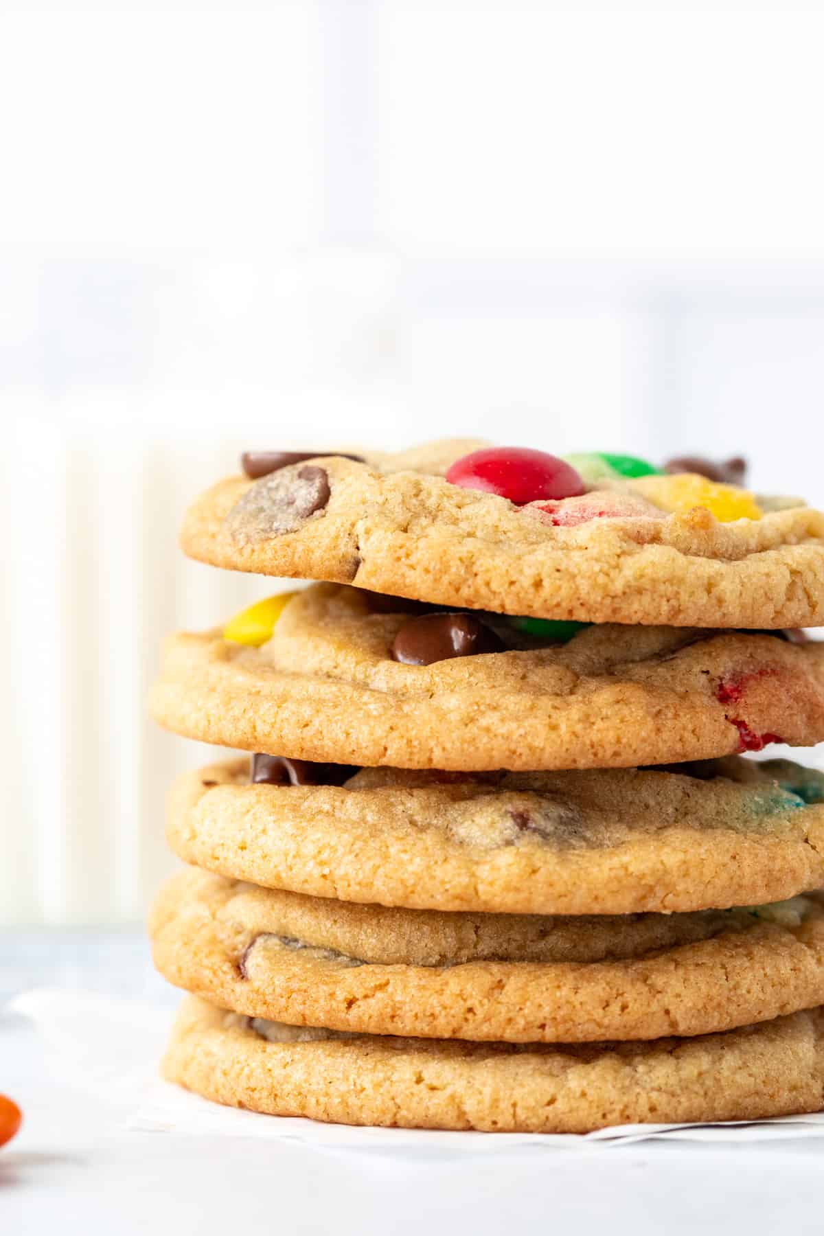 Stack of 5 M&M chocolate chip cookies with glass of milk
