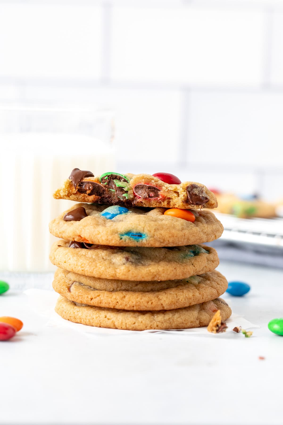 Stack of M&M chocolate chip cookies with a glass of milk