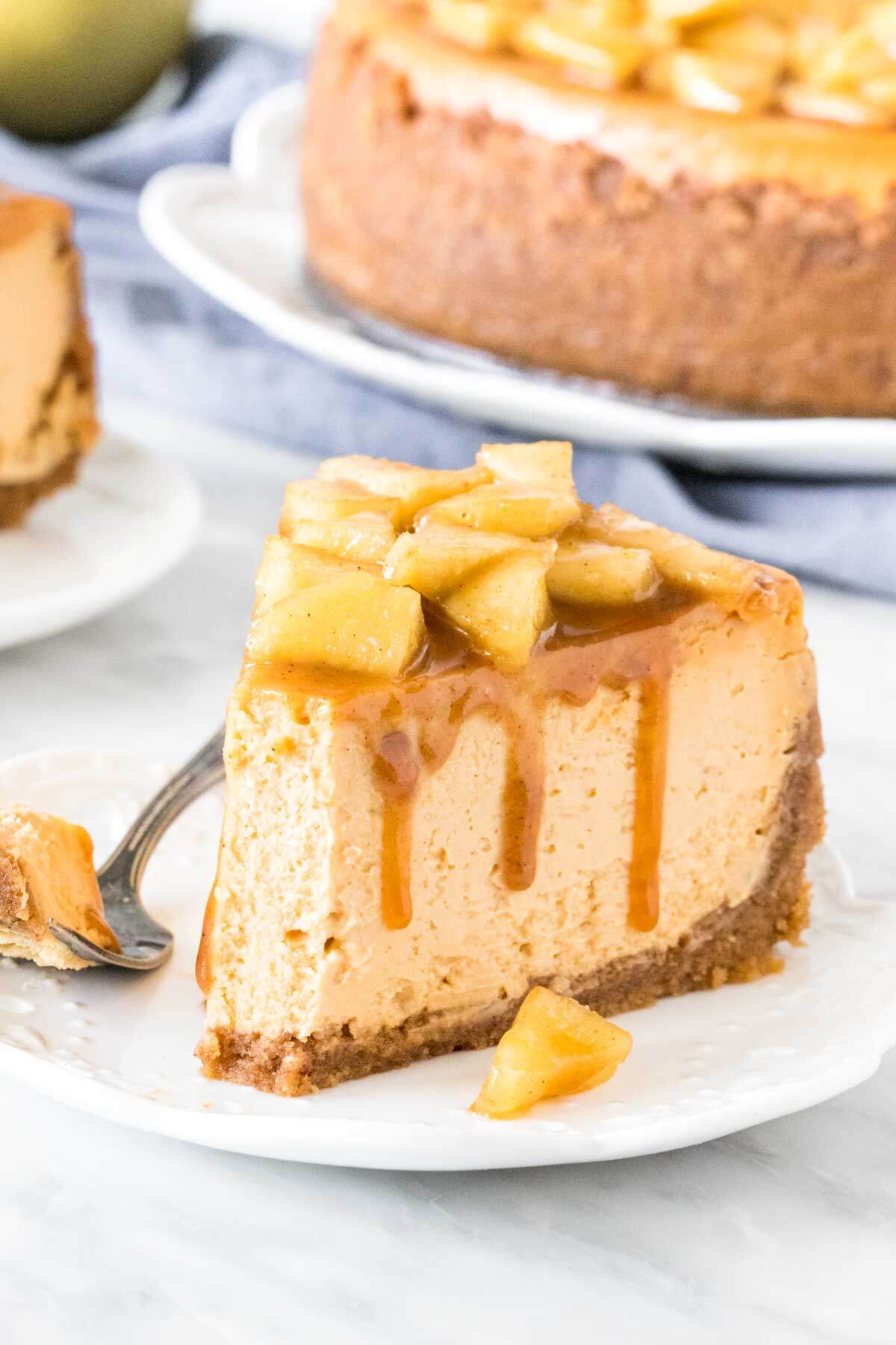 Slice of caramel cheesecake topped with cinnamon apples with a bite taken out of it. 