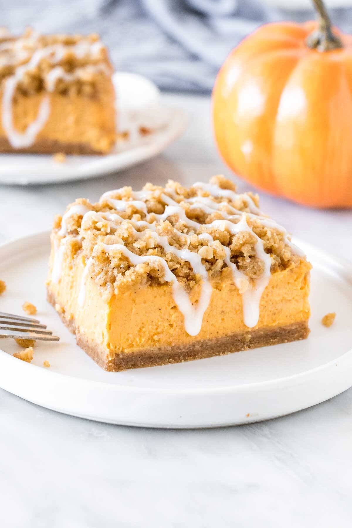 A square piece of pumpkin cheesecake streusel bars on a plate.