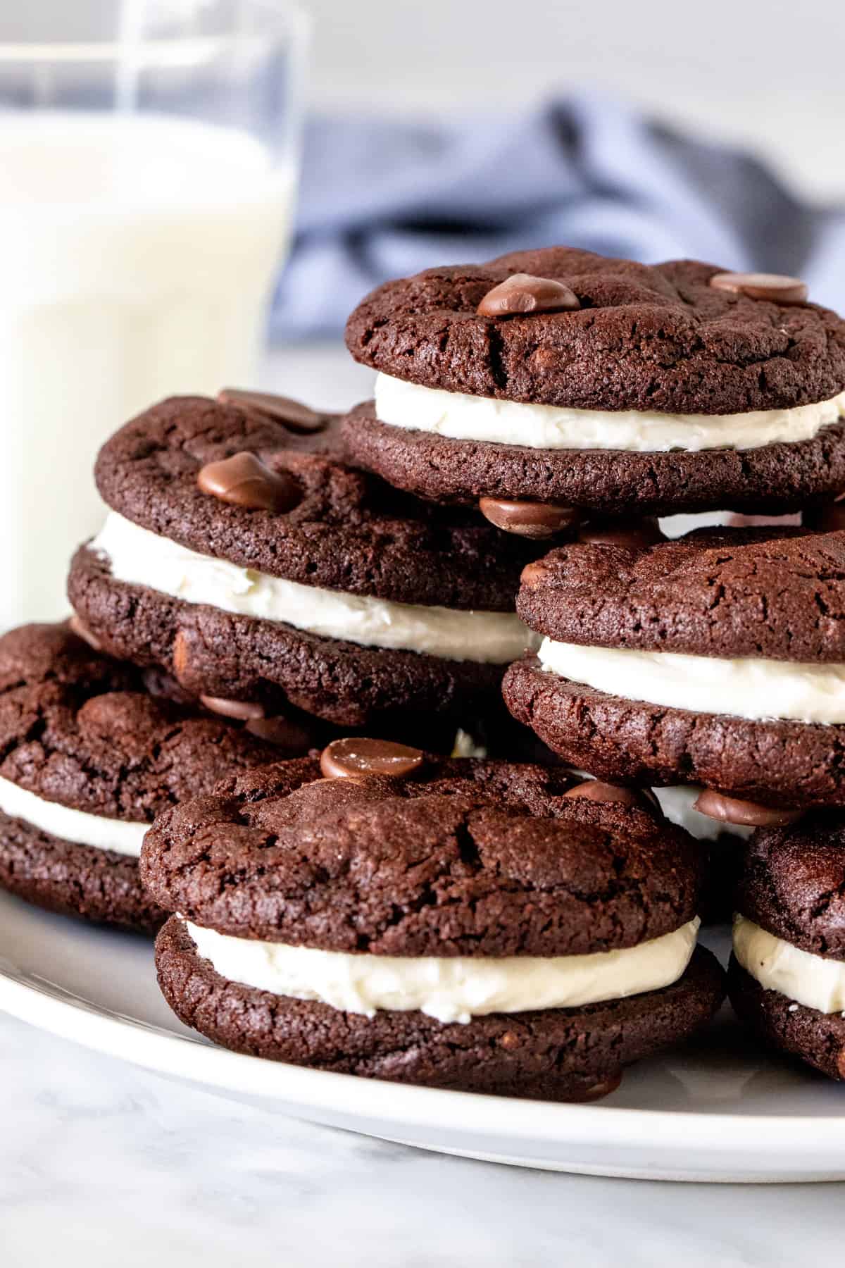 Plate of chocolate sandwich cookies with a glass of milk. 