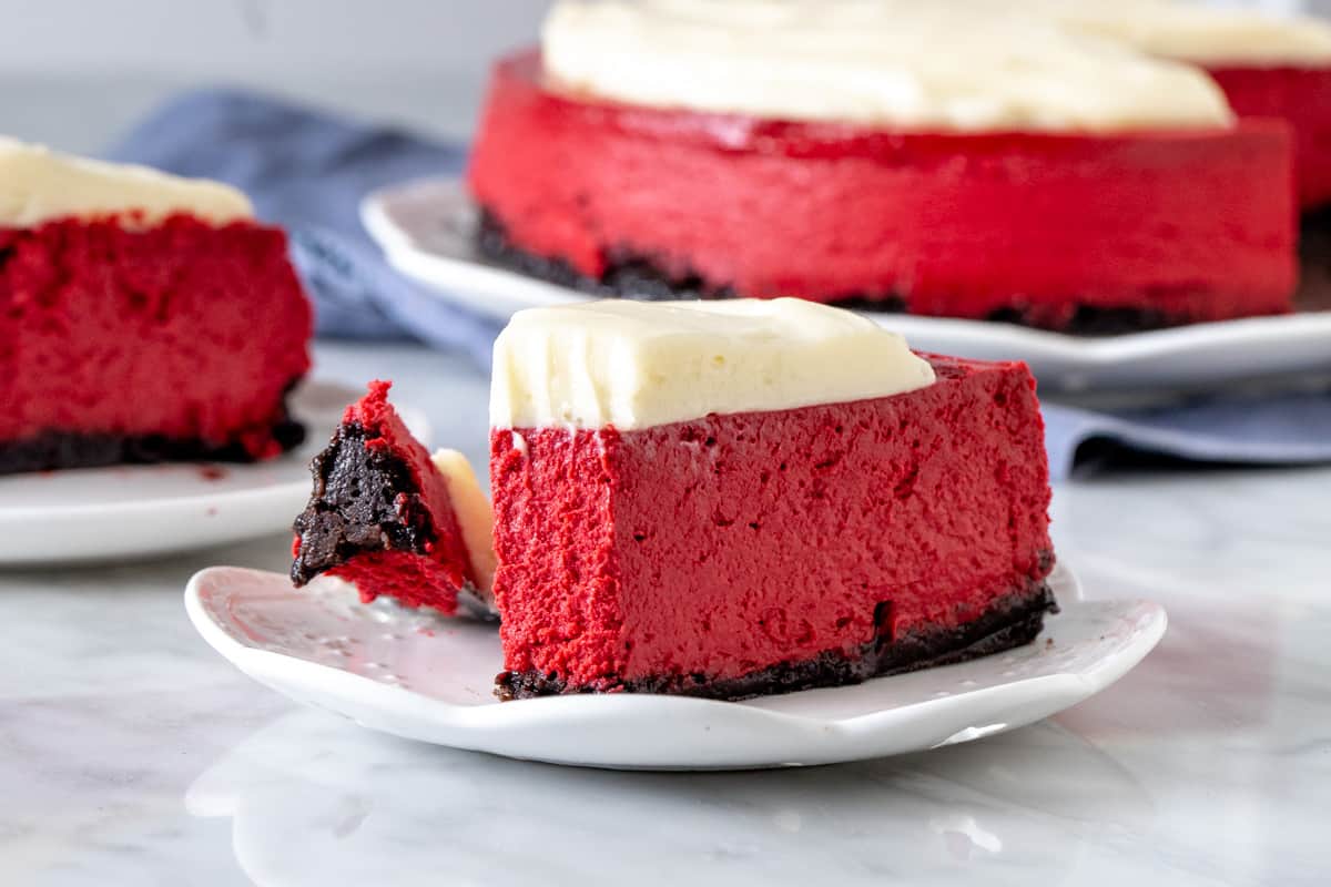 Slice of red velvet cheesecake with a bite taken out of it.