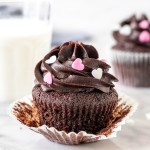 Chocolate cupcake with chocolate frosting and a glass of milk.