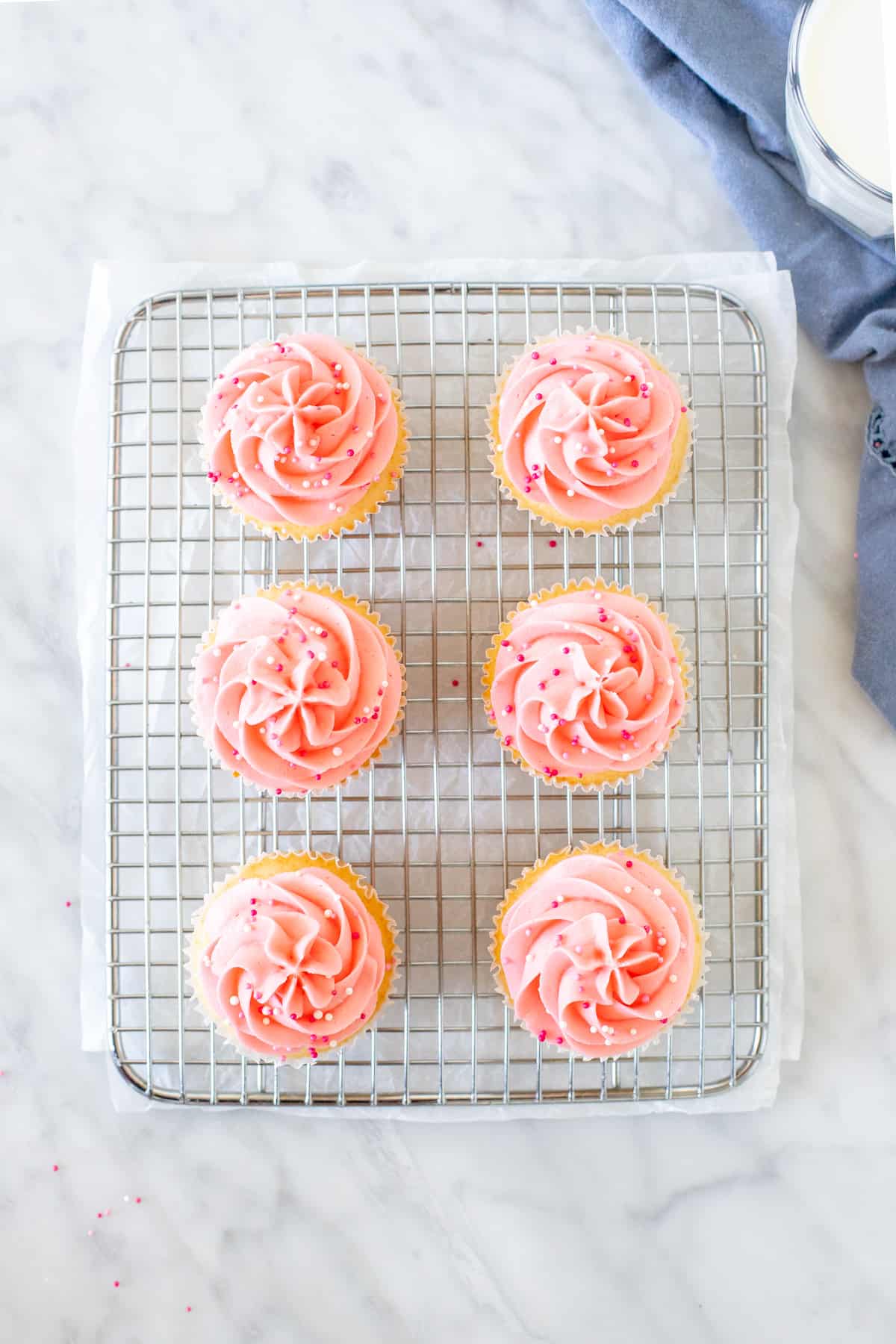 6 pink cupcakes on a cooling rack.