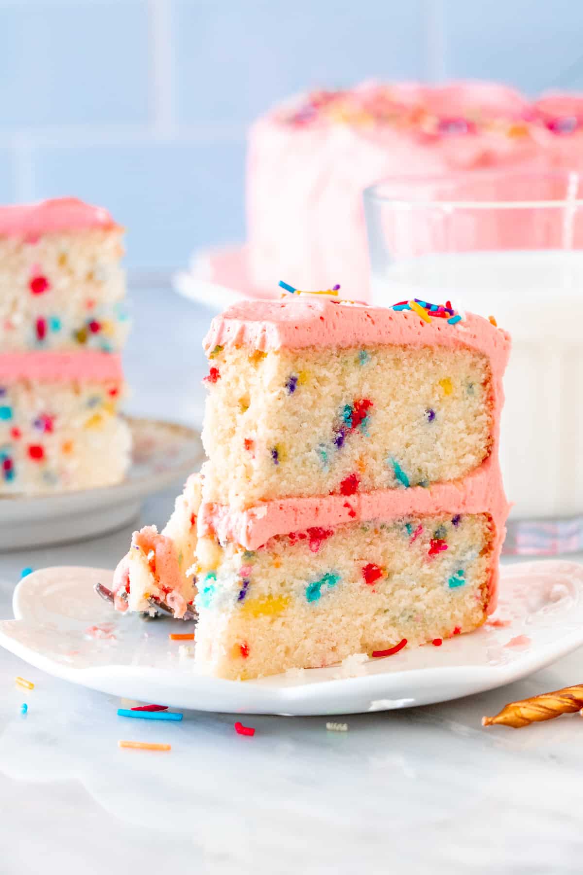 Slice of sprinkle cake with pink frosting