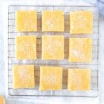 9 lemon bars on a cooling rack sprinkled with powdered sugar.