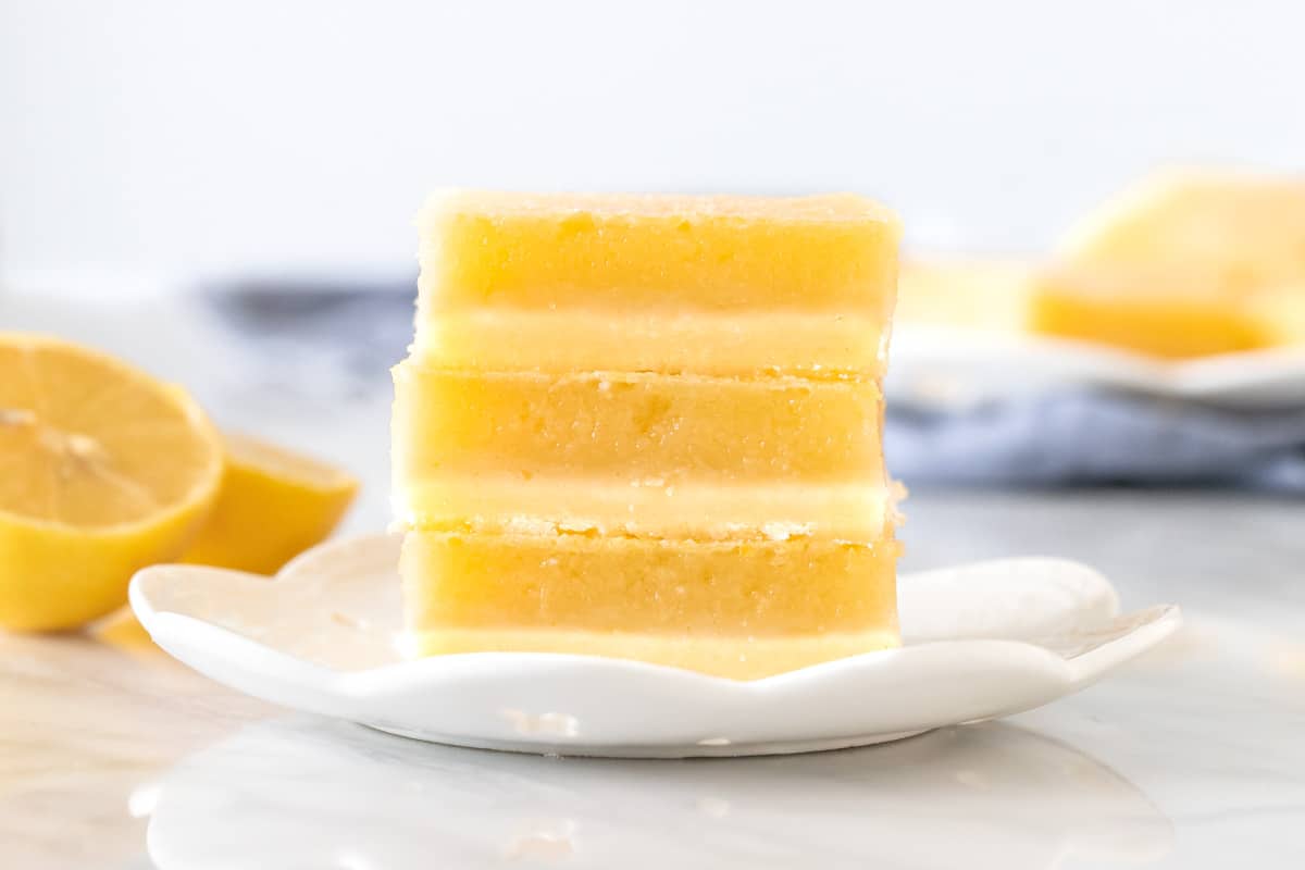 3 lemon bars stacked on a plate.